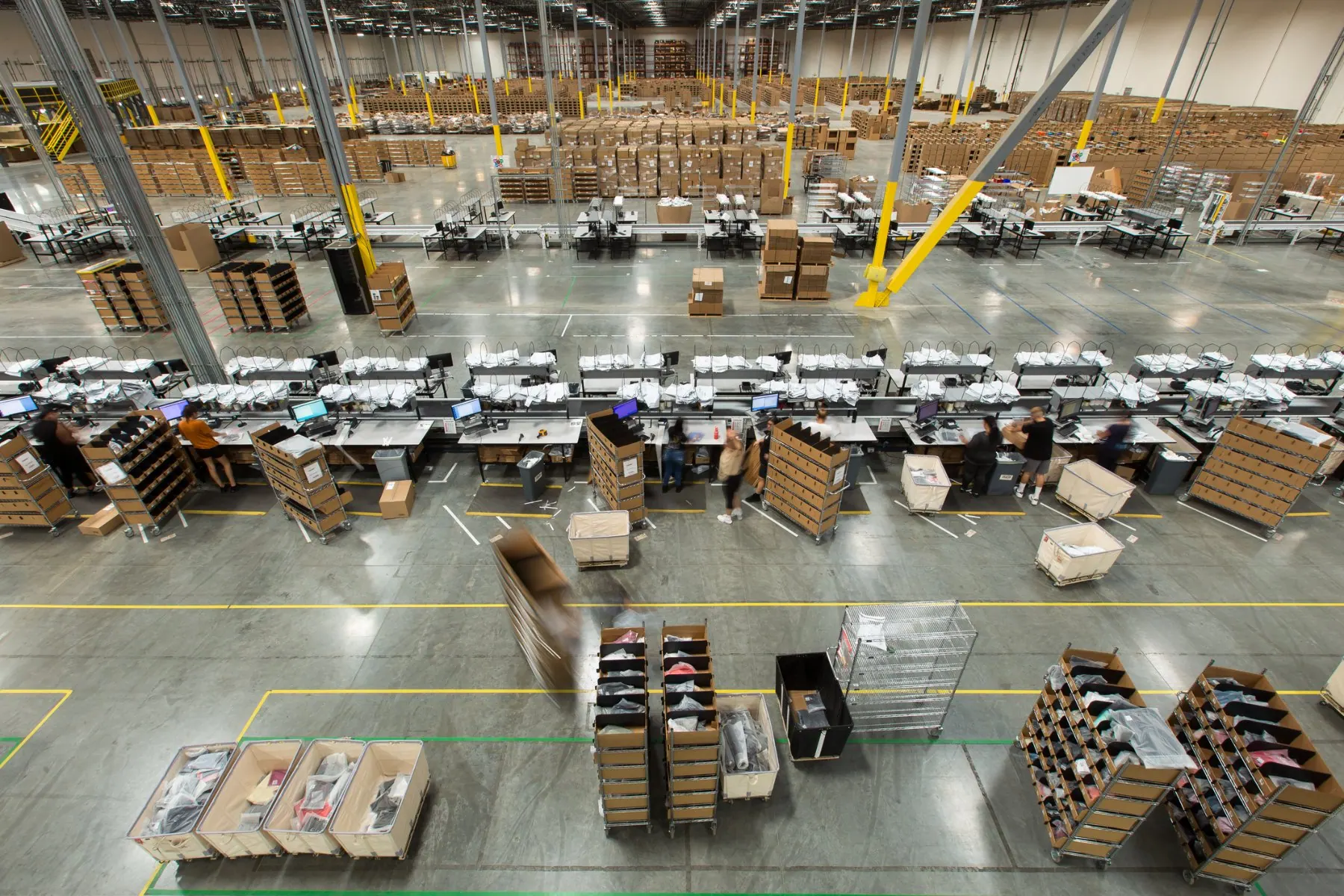 Rows of pack stations staffed across a large fulfillment floor