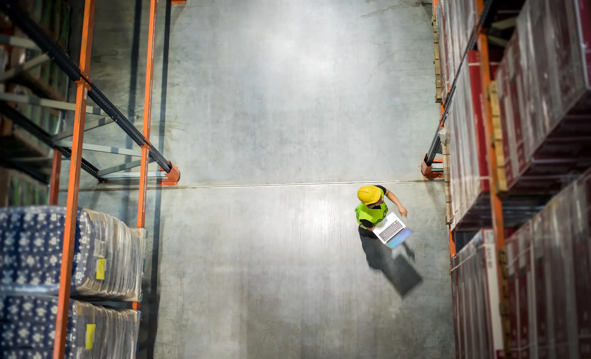 Warehouse operations floor with worker on laptop